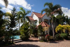 una casa con palmeras y piscina en Sir Nico Guesthouse and Resort, en Plaridel
