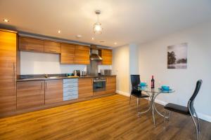 Belgrade Plaza Serviced Apartments في كوفينتري: مطبخ بدولاب خشبي وطاولة مع كراسي