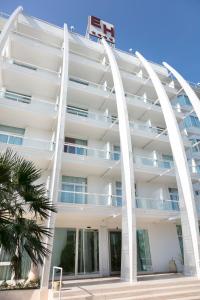 a white apartment building with white columns and a palm tree at Hotel Excelsior in Vasto