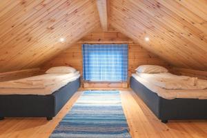 2 Betten in einem Dachzimmer mit Fenster in der Unterkunft Harriniva Adventure Resort Cabins in Muonio