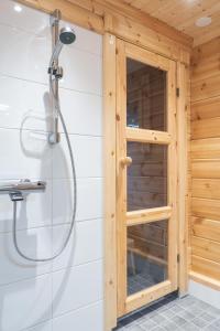 a shower with a glass door in a wooden bathroom at Harriniva Adventure Resort Cabins in Muonio