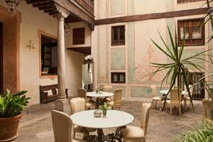a patio with tables and chairs and a plant at Hotel Casa 1800 Granada in Granada