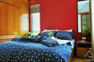 a bedroom with a blue bed with a red wall at Chez Tram Homestay in Hanoi
