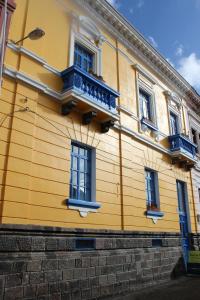 a yellow building with blue windows and a balcony at Hostal Café Tiana in Latacunga