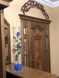 eine Vase mit einer blauen Blume auf einem Tisch neben einer Tür in der Unterkunft Europe Hotel Brody in Brody