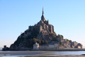 a castle on an island in the water at Le Mouton Blanc in Le Mont Saint Michel