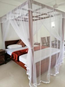 希卡杜瓦的住宿－Hikka Lagoon，卧室配有带白色窗帘的天蓬床