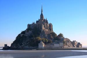 a castle on an island in the water at Les Terrasses Poulard in Le Mont Saint Michel