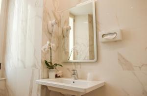 bagno bianco con lavandino e specchio di Hotel Palladium Palace a Roma