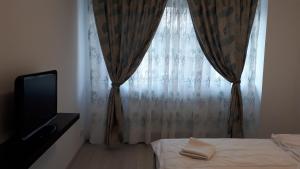 a bedroom with a bed and a window with a television at Tibiscum Apartament, Bucuresti in Bucharest