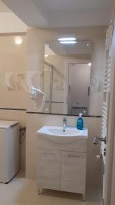 a white bathroom with a sink and a mirror at Tibiscum Apartament, Bucuresti in Bucharest