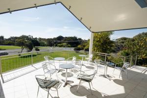 a patio with tables and chairs and a view of a field at Robetown Motel in Robe