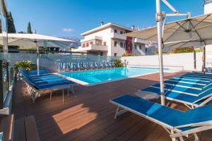 a row of blue lounge chairs next to a swimming pool at Hotel Miorelli in Nago-Torbole