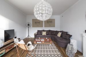 a living room with a couch and a chandelier at L'ecume by Cocoonr in Saint-Coulomb