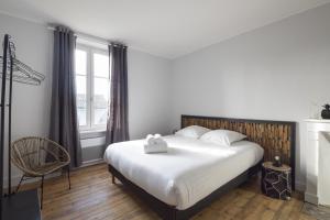 a bedroom with a bed and a chair and a window at L'ecume by Cocoonr in Saint-Coulomb