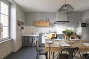 a kitchen with a wooden table and chairs in a room at L'ecume by Cocoonr in Saint-Coulomb