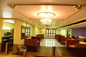 a restaurant with tables and chairs and a chandelier at Hotel Chembiyan in Pudukkottai