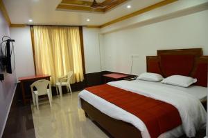 a bedroom with a large bed and a desk and chairs at Hotel Chembiyan in Pudukkottai