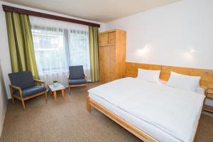 a bedroom with a large white bed and two chairs at Pension Simona in Harrachov