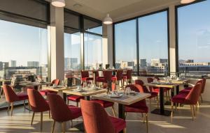 un restaurante con mesas, sillas y ventanas grandes en Résidence Odalys Nantes Cité des Congrès en Nantes