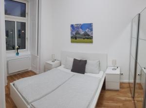 ein weißes Schlafzimmer mit einem Bett und zwei Fenstern in der Unterkunft Central Living - Naschmarkt in Wien