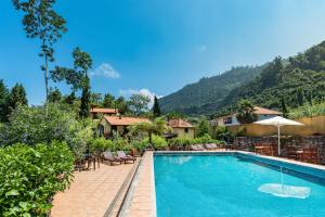 a swimming pool with tables and chairs and a mountain at Pestana Quinta do Arco Nature & Rose Garden Hotel in Arco de São Jorge