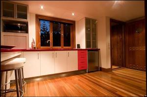 a kitchen with white cabinets and a red counter top at Cottage In The Woods - Formerly King Ludwigs Cottage in Maleny