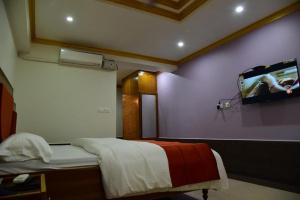 a room with a bed with a tv on the wall at Hotel Chembiyan in Pudukkottai