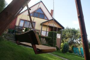 a swing in front of a house at Agrodomki Okej - Dom Oleńka in Gardna Wielka