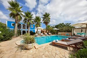 a swimming pool with lounge chairs and a blue house at Villa Can Coves in Sant Miquel de Balansat