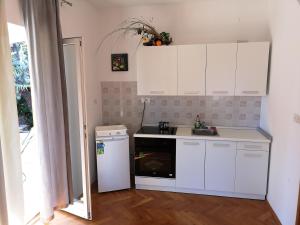 a kitchen with white cabinets and a sink and a dishwasher at Cerco in Lovran