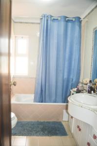 uma casa de banho com uma cortina de chuveiro azul e uma banheira e lavatório. em Beach House in Vilamoura: Terrace+pool em Vilamoura