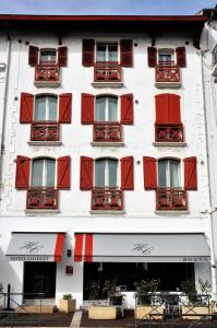 un grand bâtiment blanc avec des fenêtres à volets rouges dans l'établissement Hotel Colbert, à Saint-Jean-de-Luz