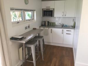 a kitchen with white cabinets and a counter with stools at Portree Garden Room in Portree