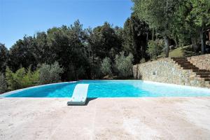 una piscina con un banco junto a una pared de piedra en Exclusive Tuscany Villa, en Civitella in Val di Chiana
