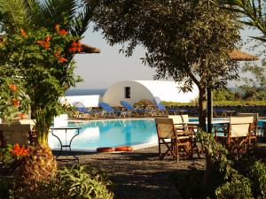 a pool with chairs and a table and a building at Kalimera Hotel in Akrotiri