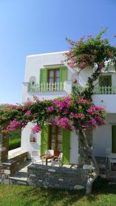 un edificio blanco con flores rosas. en Elena Studios & Apartments, en Piso Livadi