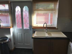 una cocina con fregadero y una puerta con ventanas en The Bungalow, en Billericay 17 fotos más