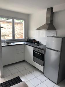 a white kitchen with a refrigerator and a sink at JOLIE PETITE MAISON près PARC DES EXPOS RER CDG ARENA in Villepinte +2 photos