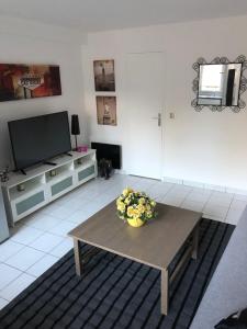 una sala de estar con una mesa con flores. en JOLIE PETITE MAISON en Villepinte