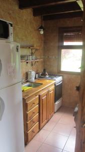 a kitchen with a white refrigerator and a sink at Cabañas Peñi Huen in Lago Puelo