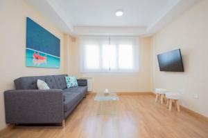 uma sala de estar com um sofá e uma televisão de ecrã plano em EnjoyGranada EMIR 3F - POOL, GYM & Free Parking em Granada