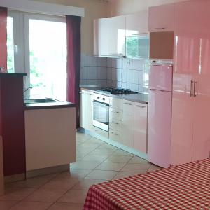 a kitchen with white cabinets and a pink refrigerator at Pool Apartment Knezevic in Novalja