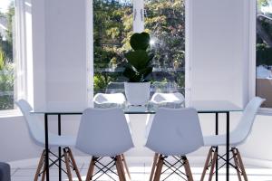 a dining room with a table and four white chairs at Beautiful Bell Rock - partial inverter in Plettenberg Bay