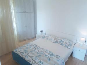 a bedroom with a white bed with a blue blanket at Apartments Hropić in Lastovo