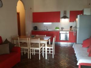 cocina con armarios rojos, mesa y sillas en Seaview House, en Santa María