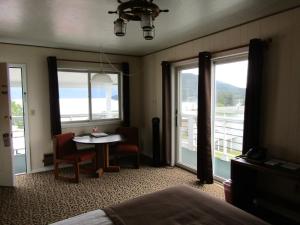 a room with a bed and a table and windows at Captain's Choice Motel in Haines