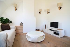 - un salon avec un canapé blanc et une télévision dans l'établissement La Citadine-Gîte citadin, à Neufchâteau
