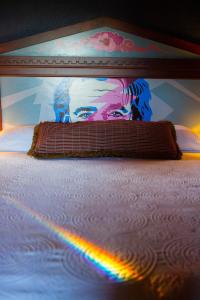 a bed with a rainbow in front of a painting at McMenamins Grand Lodge in Forest Grove