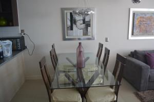 una mesa de comedor de cristal con sillas y un jarrón. en Costa Puyai - Exclusivo Departamento en primera línea- Playa Punta Puyai, en Papudo